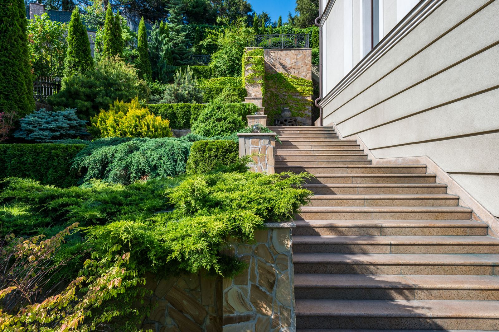 Terraced stone retaining walls and stairs winding through a landscaped hillside garden