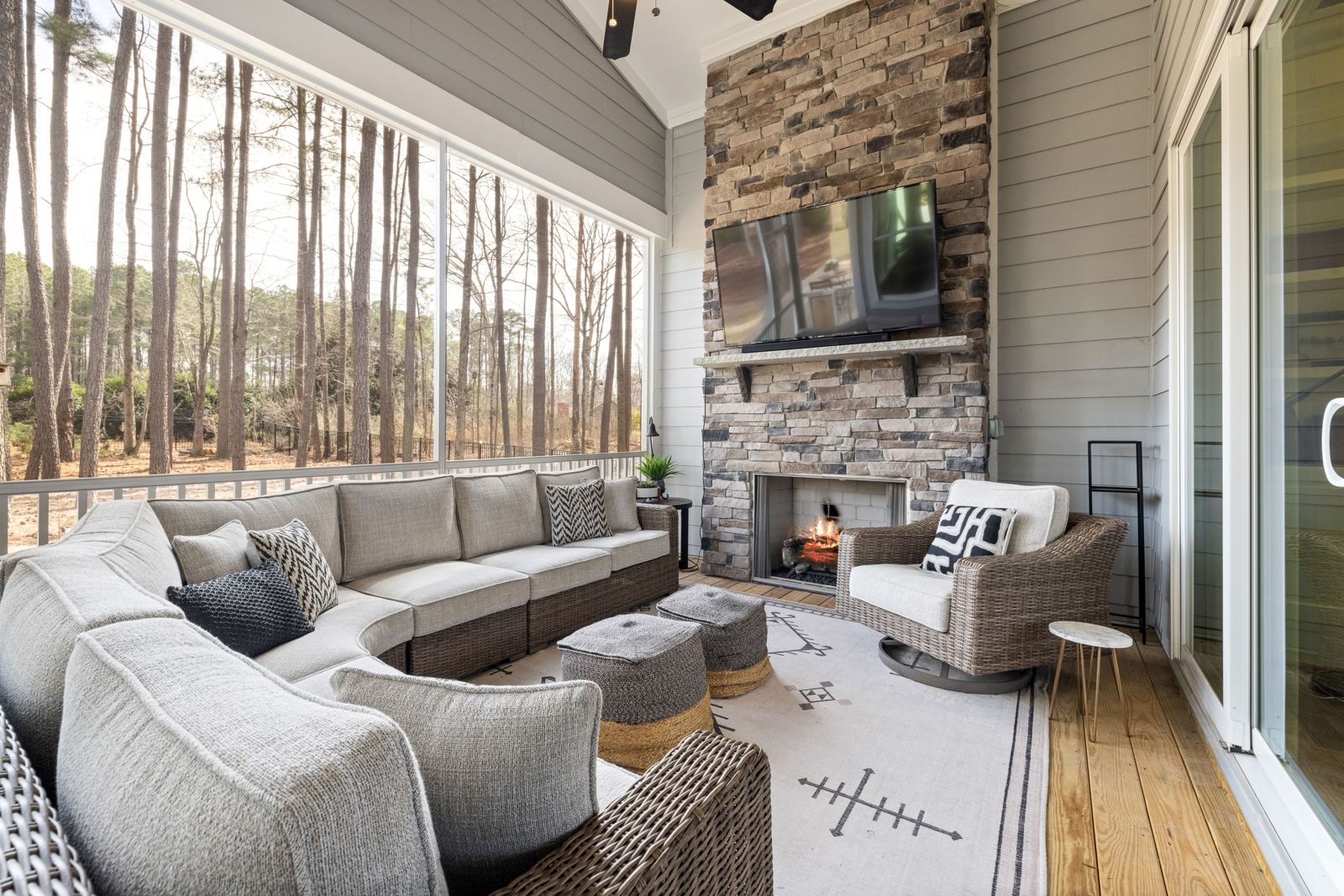 Screened porch with a stone fireplace, TV, and cushioned seating