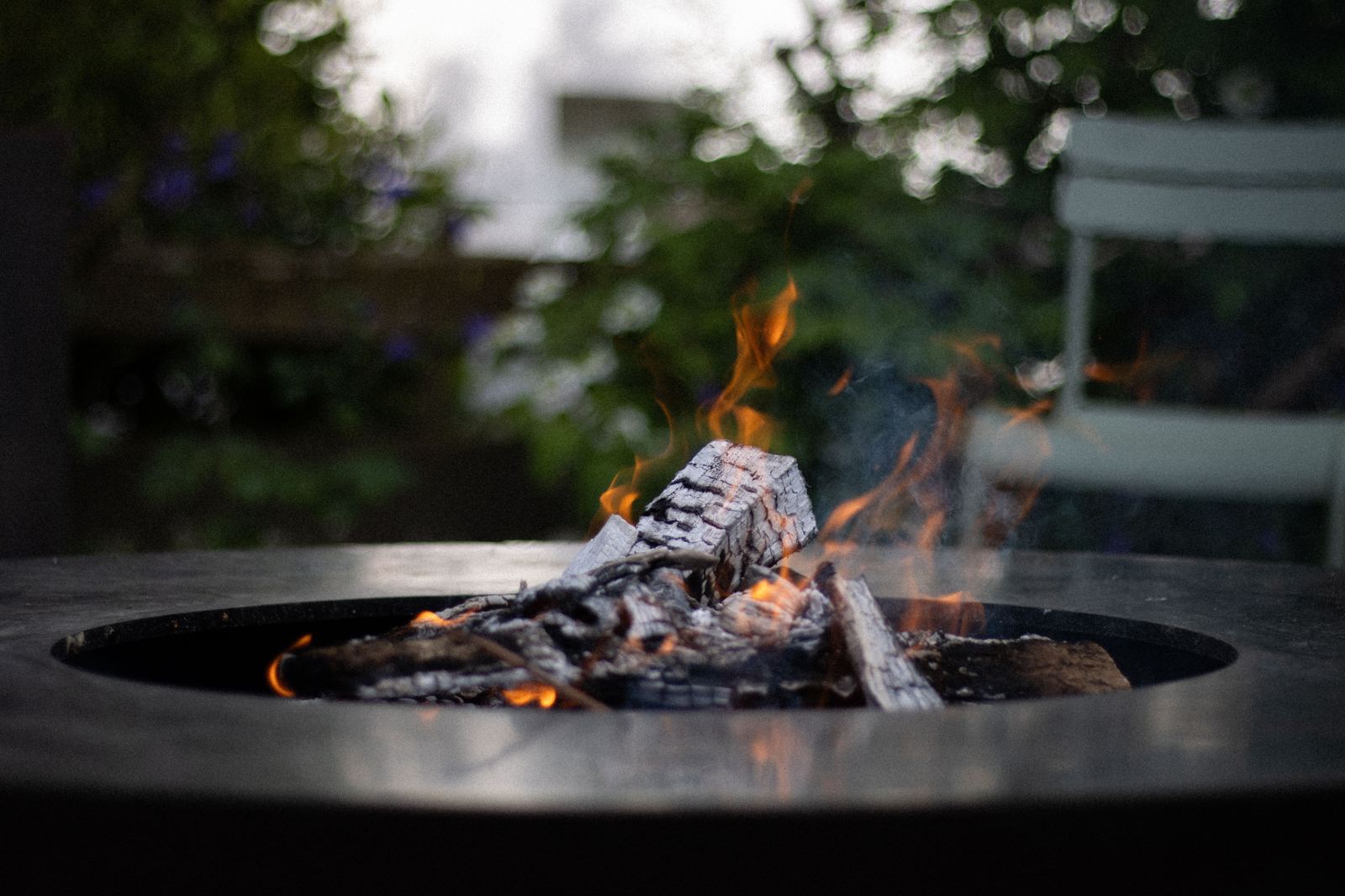 Close-up of a fire pit with burning logs on a backyard patio