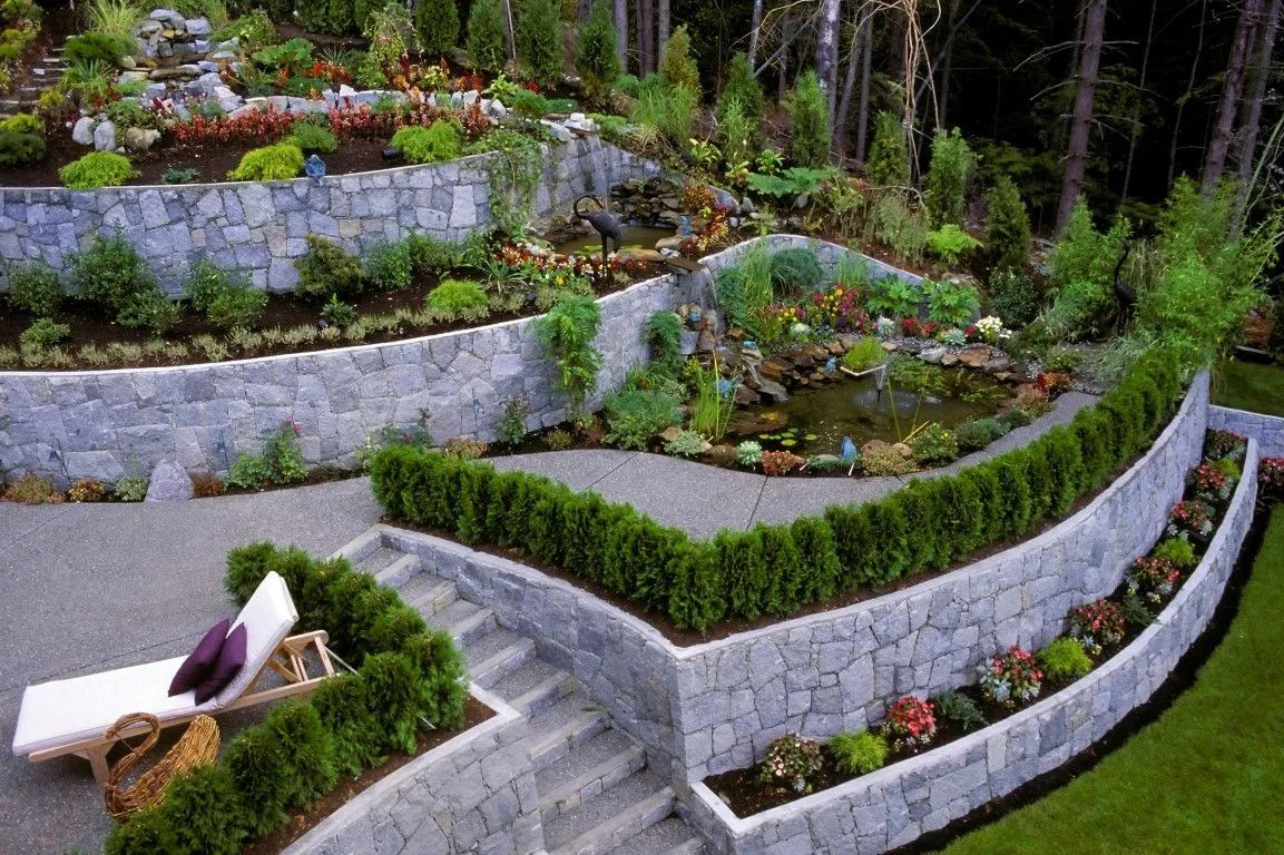 Tiered stone retaining walls terracing a garden with a small pond