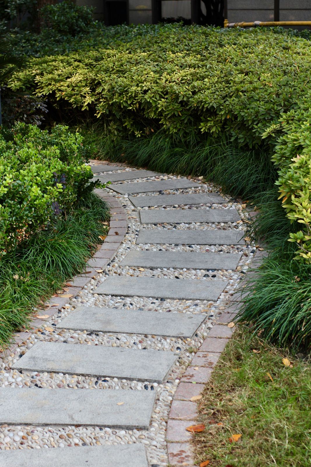 Stepping-stone concrete path bordered by loose pebbles through a garden