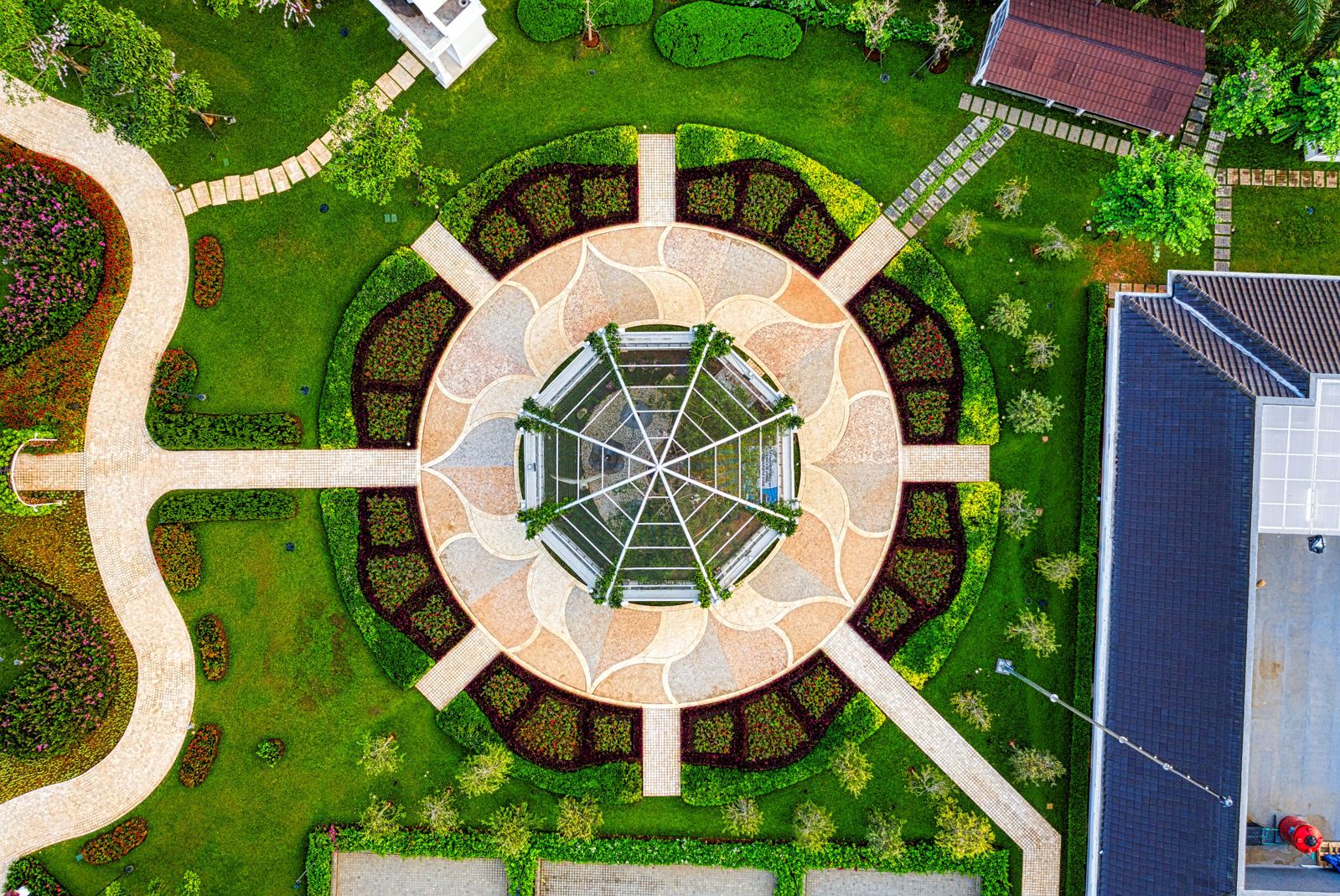 Aerial view of a remodeled backyard with a circular paver patio, hedges, and a glass gazebo